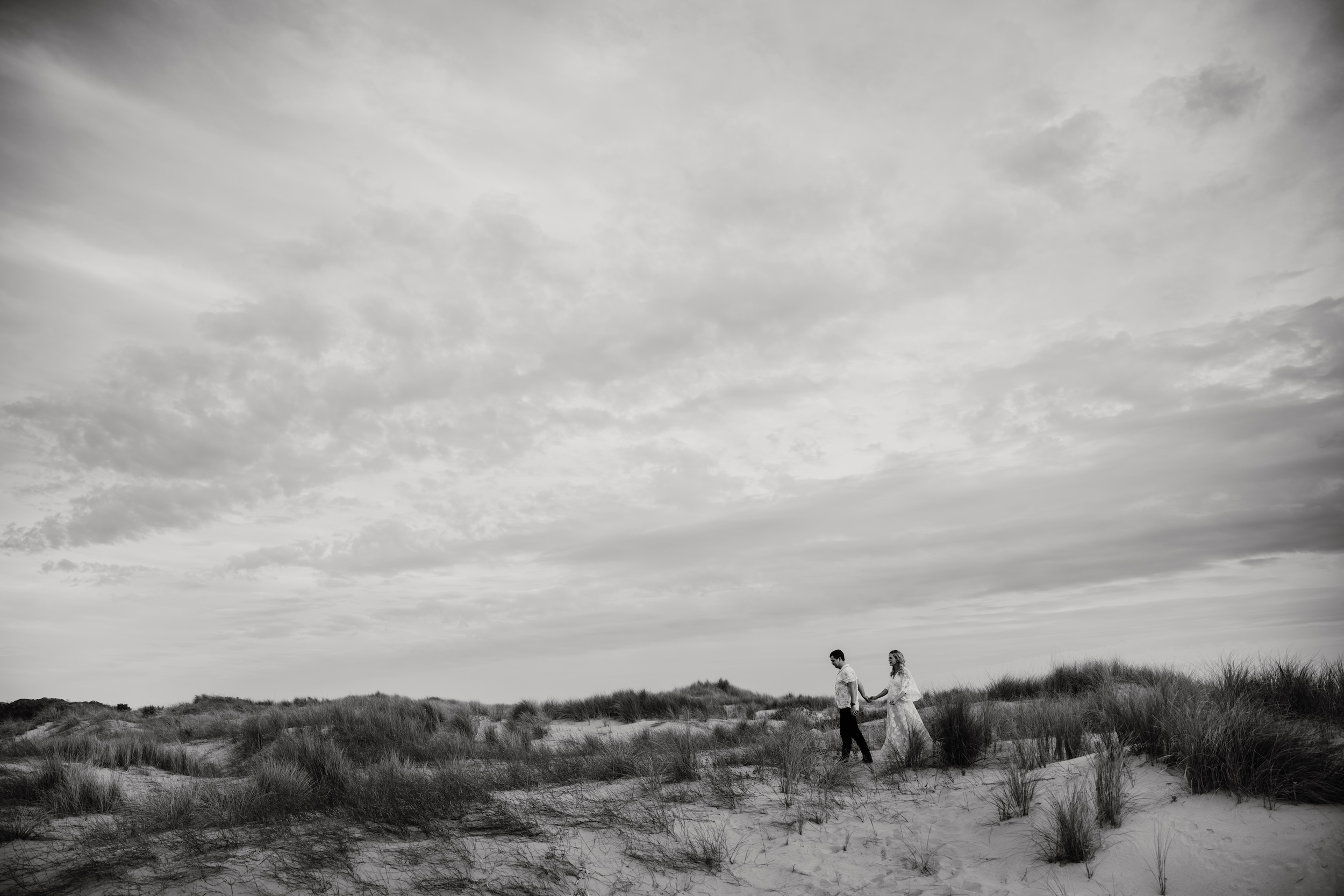 man and woman walking on grass covered beach June Richards photography